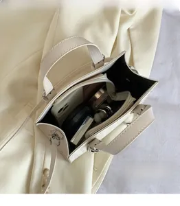 Interior view showing the spacious capacity of a cream woven crossbody bag with daily items