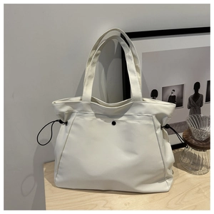 Detailed shot of white nylon tote bag with side drawstring and black metal snap pocket