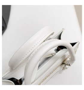 Détail des poignées du sac à main en cuir blanc avec coutures précises et fermeture éclair