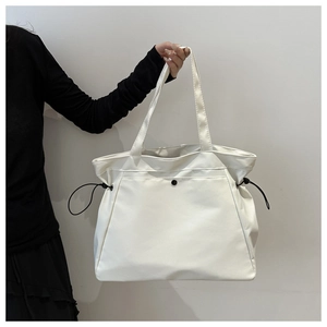 Detail of white large capacity tote bag featuring black drawstring and round buckle