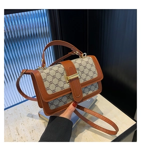 Détail d'un sac bandoulière vintage à monogramme avec fermoir doré et cuir marron