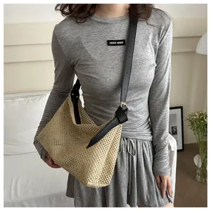 Détail de la bandoulière réglable en cuir noir et de la paille tressée du sac
