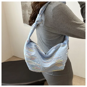 Détail du sac dumpling en nylon bleu clair avec broderies vagues et bandoulière nouée