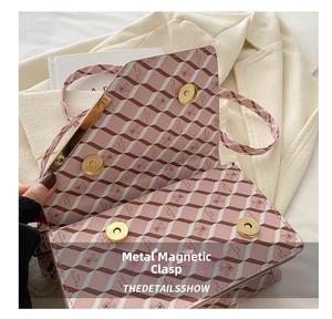 Close-up of golden magnetic snap fasteners on pink geometric printed crossbody bag