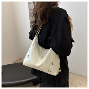 Detail of cream PU leather shoulder bag with embossed crocodile texture and silver butterflies