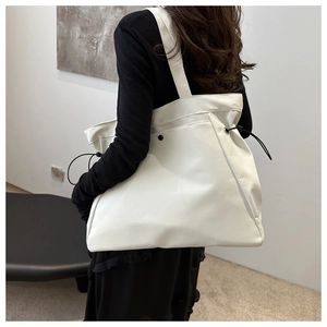 Close-up of beige tote bag side showing adjustable black drawstring and premium texture