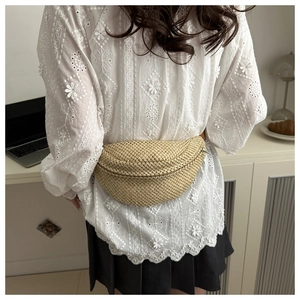 Détail d'un sac ceinture en paille tissé main avec fermeture éclair en métal stylé