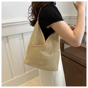 Détail du sac seau en paille tressée avec ouverture en V et bordure en cuir marron