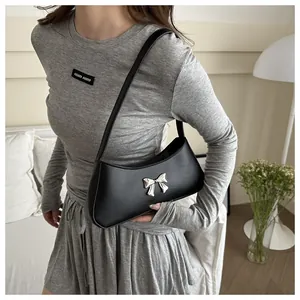 Détail d'un sac sous le bras en cuir PU noir avec un nœud en métal argenté