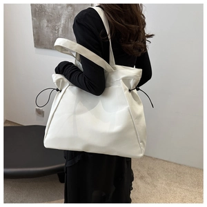 Detailed side view of white tote bag with drawstring texture and wide shoulder strap