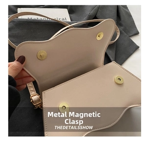 Detail shot of the golden magnetic cylindrical buckles on a beige faux leather handbag