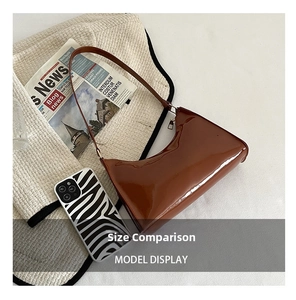 Detailed view of a glossy dark brown underarm bag next to a zebra phone case