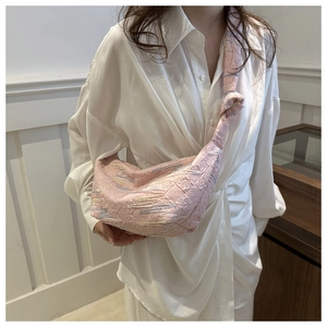 Détail du sac à bandoulière rose texturé avec broderie ondulée et sangle nouée