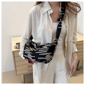 Détail du sac bandoulière noir avec des motifs de broderie arc-en-ciel en zigzag colorés