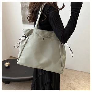 Detail view of large canvas tote bag showing side drawstrings and snap button closure
