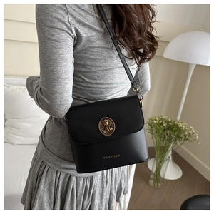 Détail du sac seau vintage noir avec emblème d'ours doré et bandoulière réglable