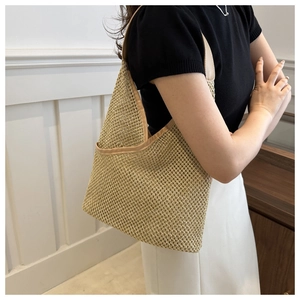 Détail d'un sac seau en paille tissée avec motif ajouré texturé et matériau beige naturel