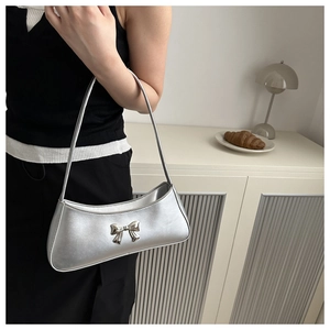 Silver metallic underarm bag with a 3D bow detail shown on shoulder with minimalist style