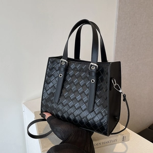 Minimalist black woven leather tote bag with top handles and detachable shoulder strap