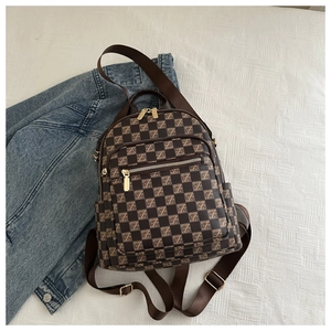 Detailed view of brown checkered pattern with Z-letter motifs and golden zippers on backpack