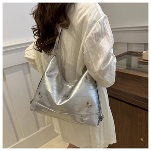 Silver PU leather shoulder bag with metallic butterfly details shown in use