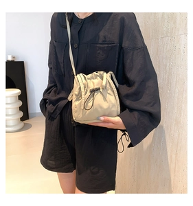 Close-up of minimalist nylon drawstring crossbody bag with pleated texture on a model
