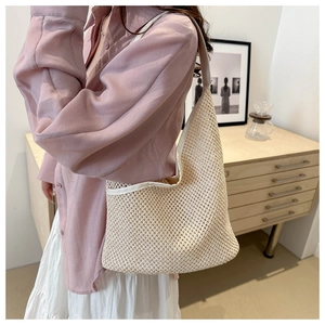 Gros plan du sac hobo en maille beige montrant la texture tricotée et les bordures blanches
