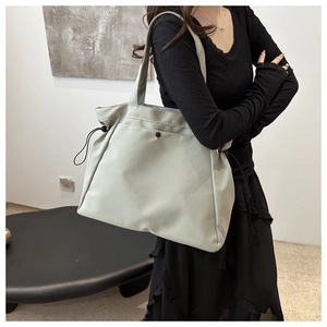 Detail of light green large capacity tote bag with side drawstring and minimalist button