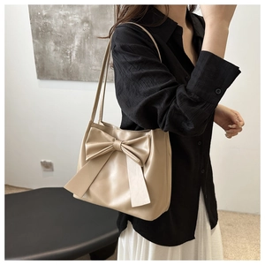 Detail of a beige bow-knot tote bag made of soft PU leather shown on shoulder