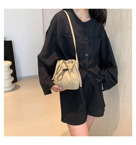 Detail of khaki nylon drawstring bucket bag with adjustable toggle closure and shoulder strap