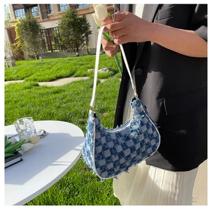 Détail du sac baguette en jean à damier bleu avec bords effilochés et bandoulière