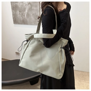 Detail of the light grey tote bag showing adjustable side drawstrings and dual straps