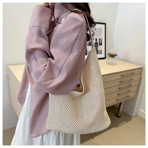 Détail du sac bandoulière tissé crème porté avec une chemise rose en décor naturel