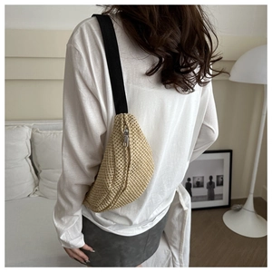 Modèle portant le sac bandoulière beige tissé en demi-lune avec sangle en toile noire