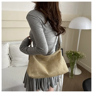 Détail du sac à bandoulière tressé beige avec sangle en cuir sur le mannequin