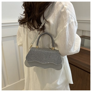 Gros plan du sac carré brillant en strass avec un design unique de bord inférieur ondulé
