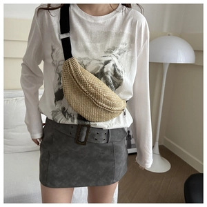 Sac ceinture en paille tressée avec sangle noire porté en bandoulière sur le torse