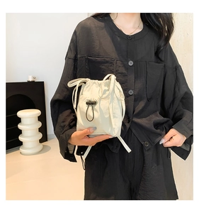 Detail view of cream drawstring bucket bag with black bungee cord and toggle fastener