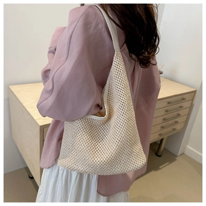 Détail du sac seau en maille tressée beige avec motif ajouré et bandoulière en cuir souple