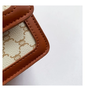 Gros plan sur le motif en toile vintage et les coutures en cuir marron du sac bandoulière