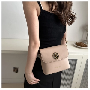 Gros plan du sac seau beige avec boucle ourson vintage et texture cuir raffinée
