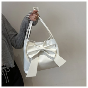 Détail d'un sac cabas en similicuir blanc avec grand nœud et poignées fines minimalistes