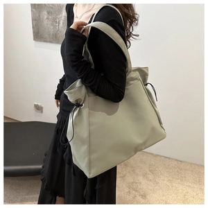 Detail of light green tote bag with drawstring side closure and smooth leather texture