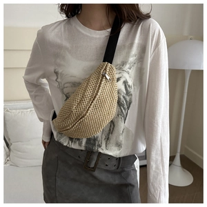 Détail du sac en paille en demi-lune avec bandoulière en nylon noir et zip argenté poli