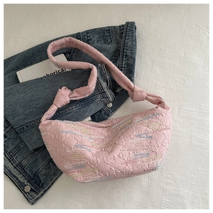 Détail du sac bandoulière en nylon matelassé rose sur une veste en jean