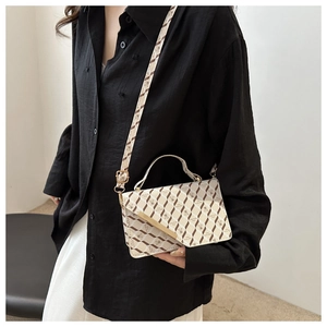 Detailed view of cream leather crossbody bag with brown pattern and gold metal hardware