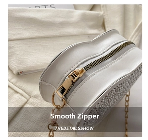Detail showing the smooth gold zipper and rhinestone texture on heart-shaped white bag
