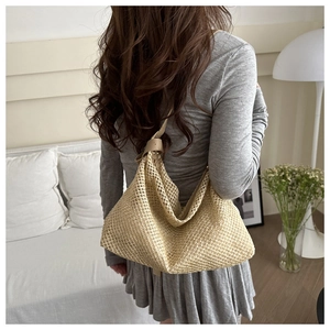 Detail of hand-woven straw crossbody bag with light brown leather strap on model