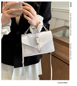 Detailed view of a white leather envelope crossbody bag with a horseshoe metal buckle