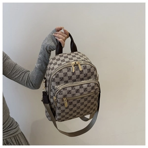 Detail of plaid backpack showing check pattern, top handle and front zipper pocket